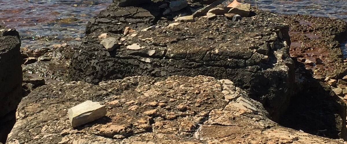 A rocky shoreline with stacked stones and a calm sea in the background.
