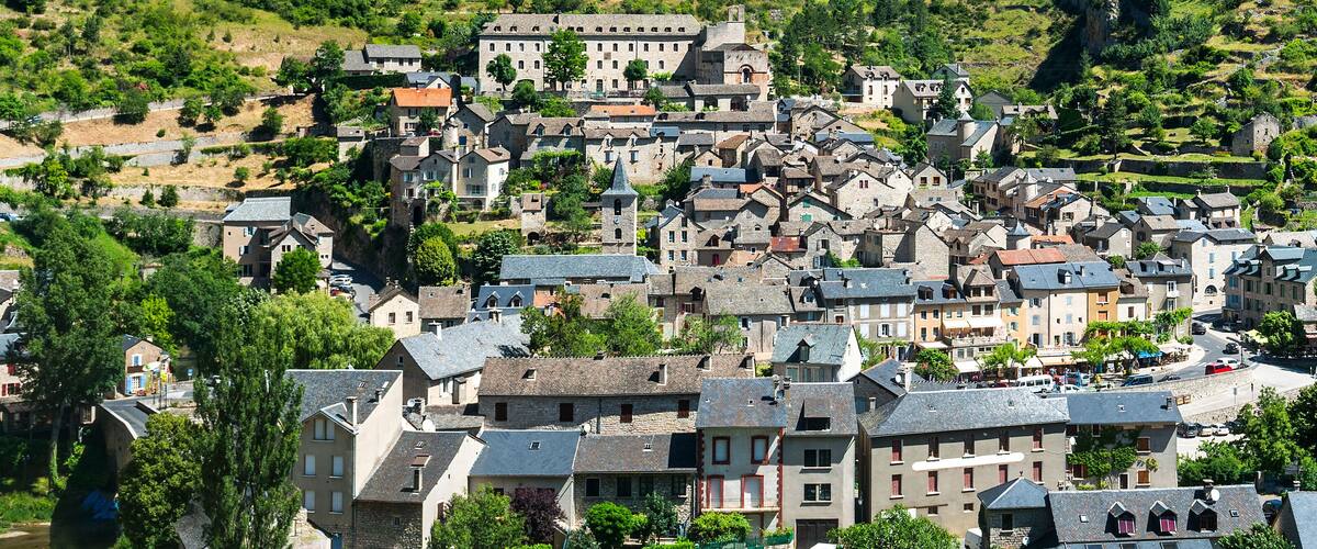 A historic town with stone buildings, a church, and a river.