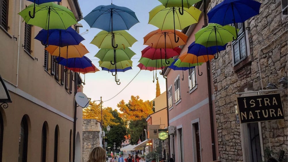 Eine Straße mit bunten Regenschirmen, die darüber hängen.