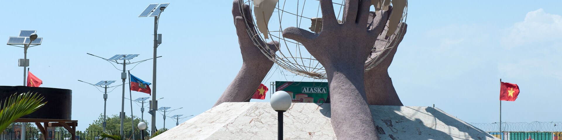 Una gran escultura de un globo terráqueo sostenido por manos, rodeada de banderas y paneles solares.