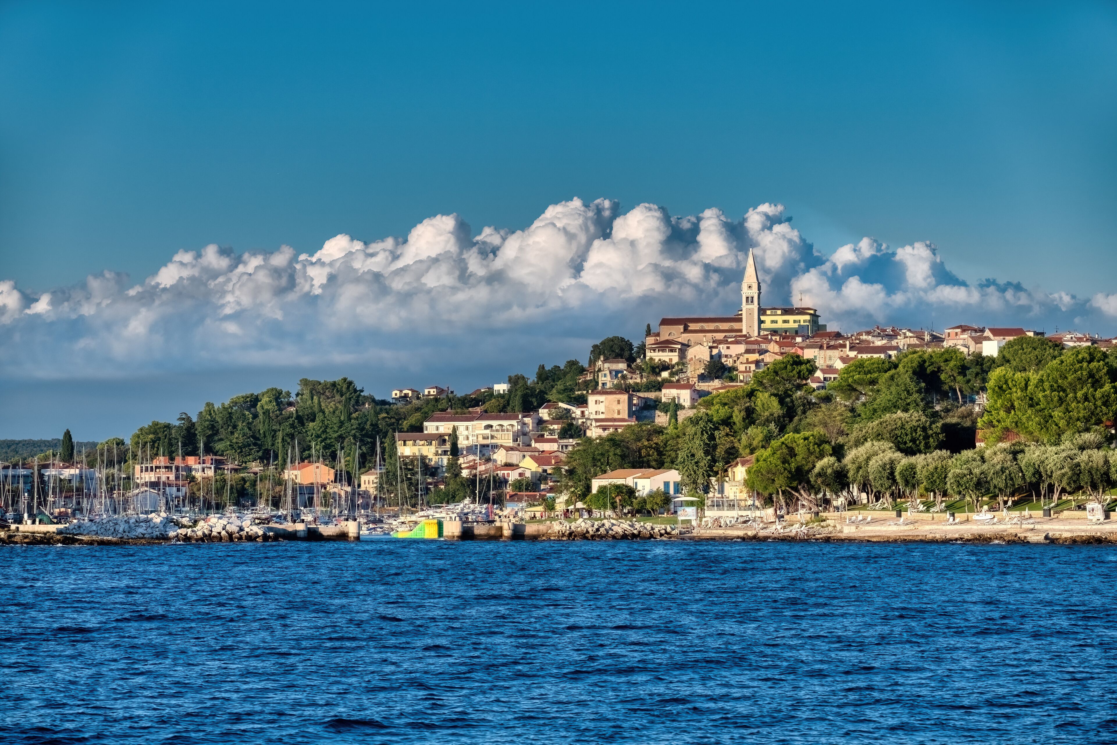 scenic coastal view of vrsar old town in istria croatia with the iconic church tower and white clouds over blue adriatic sea during daytime