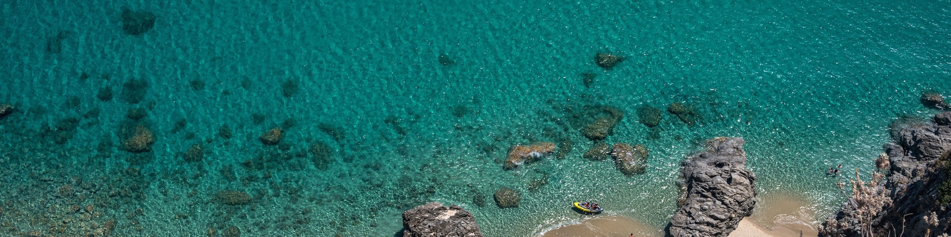 Un paisaje costero con aguas turquesas cristalinas, formaciones rocosas y una playa arenosa.