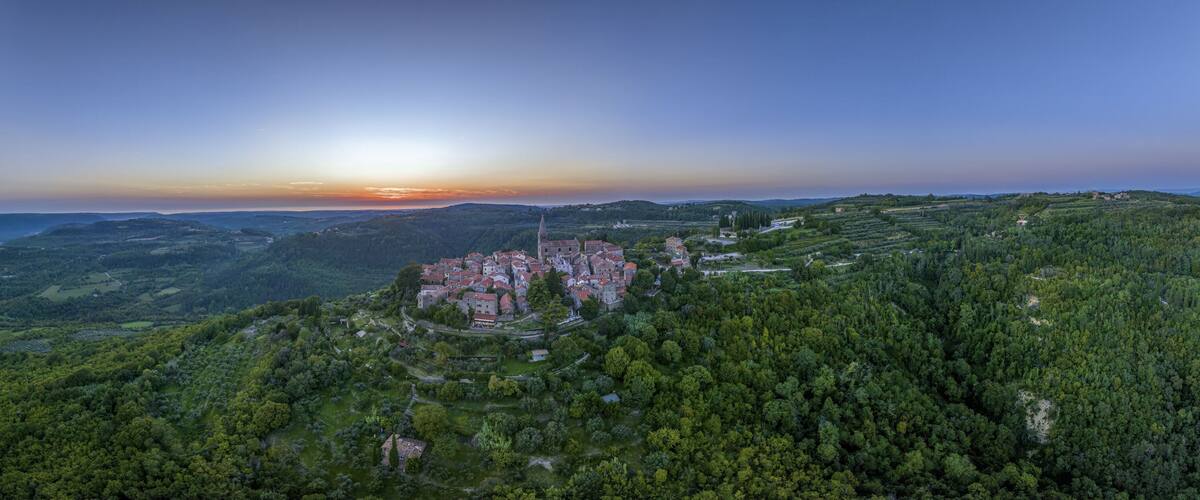 A village nestled in a valley with a prominent church and surrounding greenery.