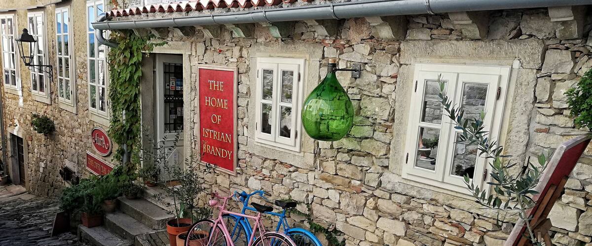 A stone building with a red sign reading "The Home of Istrian Brandy."