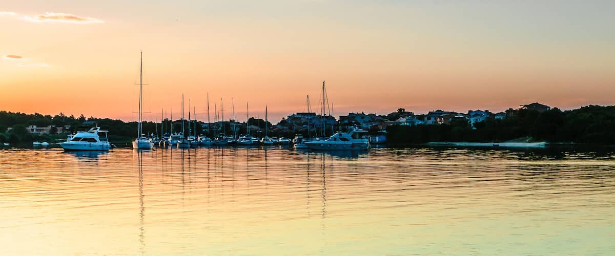 A marina with several sailboats docked at sunset.