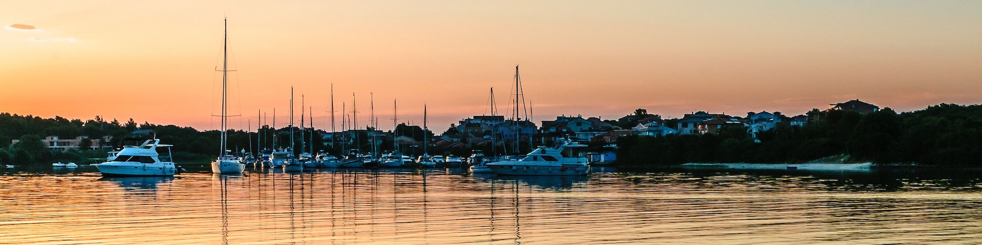 A marina with several sailboats docked at sunset.