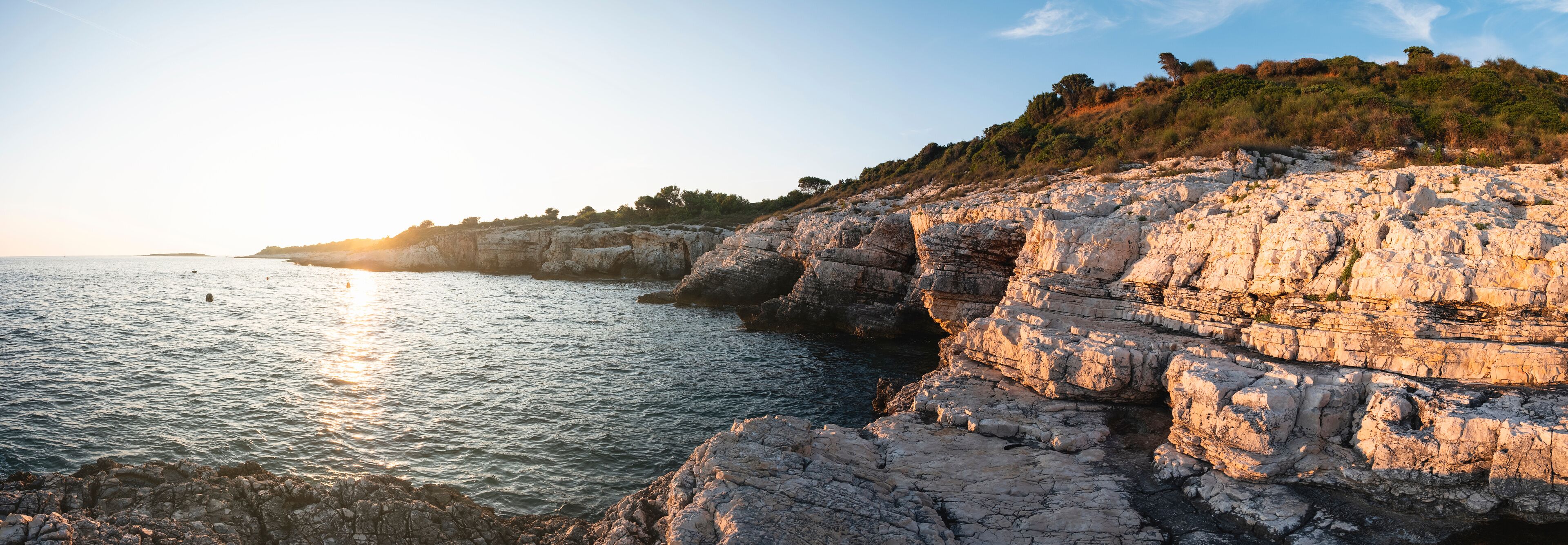 A coastal landscape with rocky cliffs and calm sea.