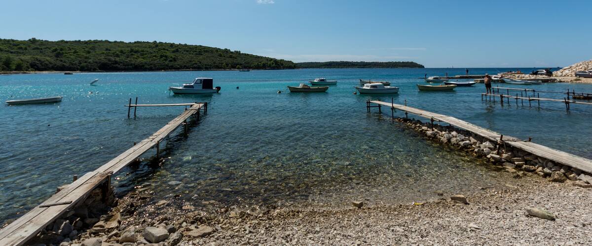 A clear blue lake with several boats docked at wooden piers.