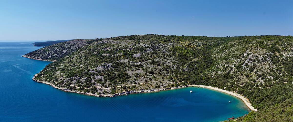 A coastal landscape with a bay, a small island, and a beach.