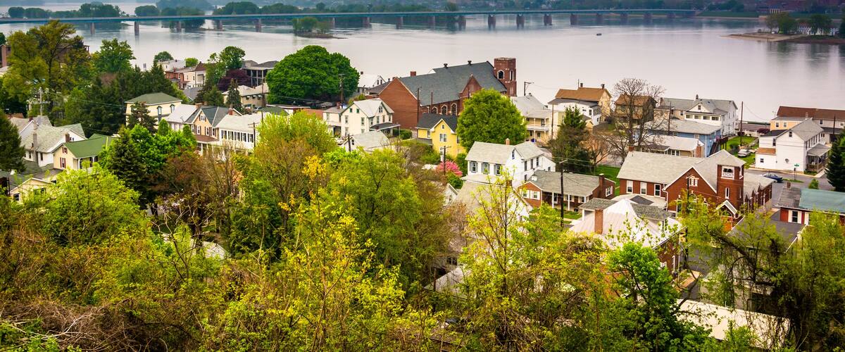 A riverside town with a bridge, houses, and greenery.