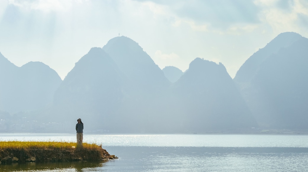 One Asian woman enjoying beautiful karst peaks landscape at Quyang Lake (Quyanghu), Baise city, Guangxi province, China