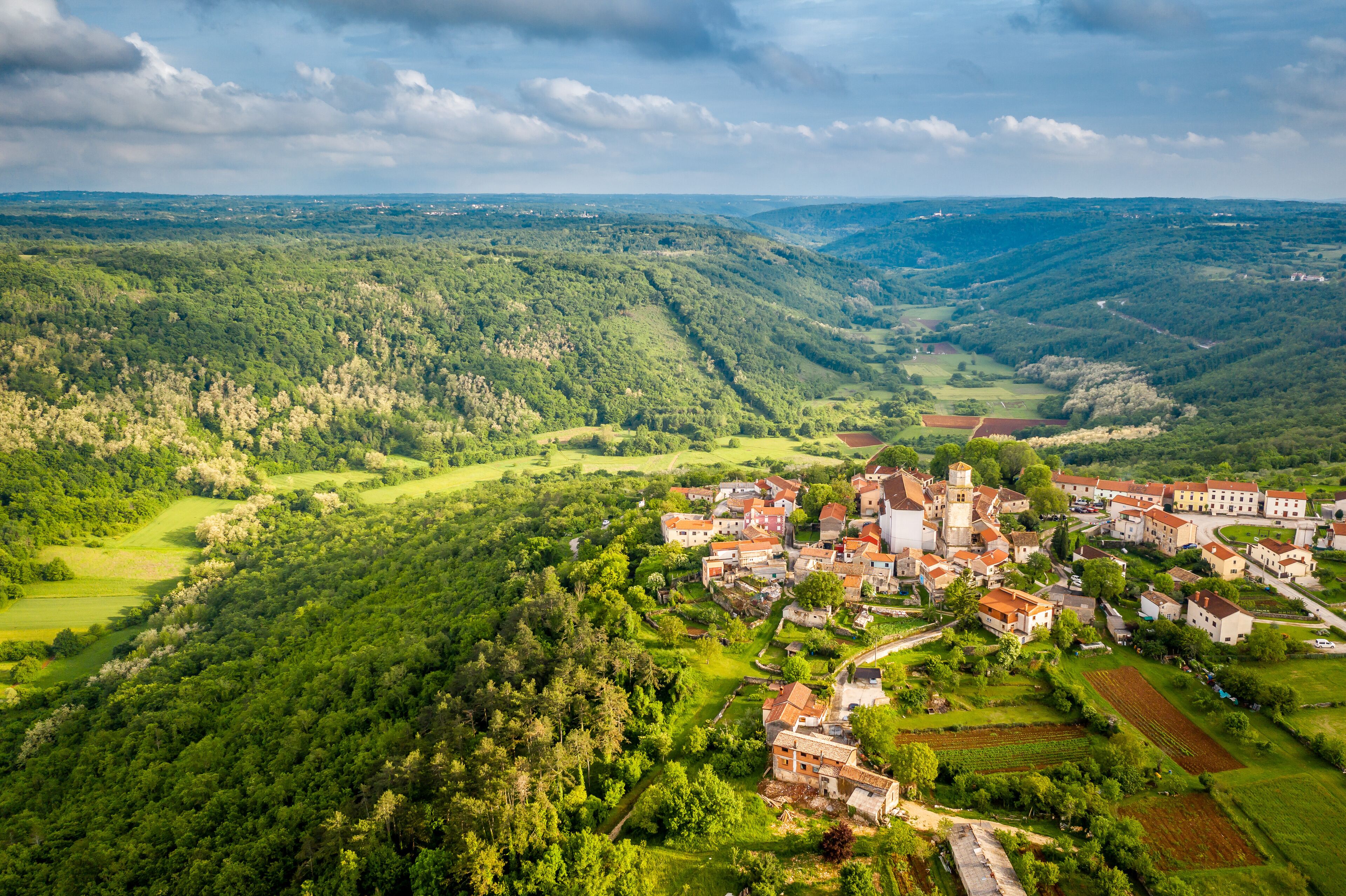 Aerial view of Romanicka crkvica sv. Kriza with mountains in the background in Tinjan, Croatia