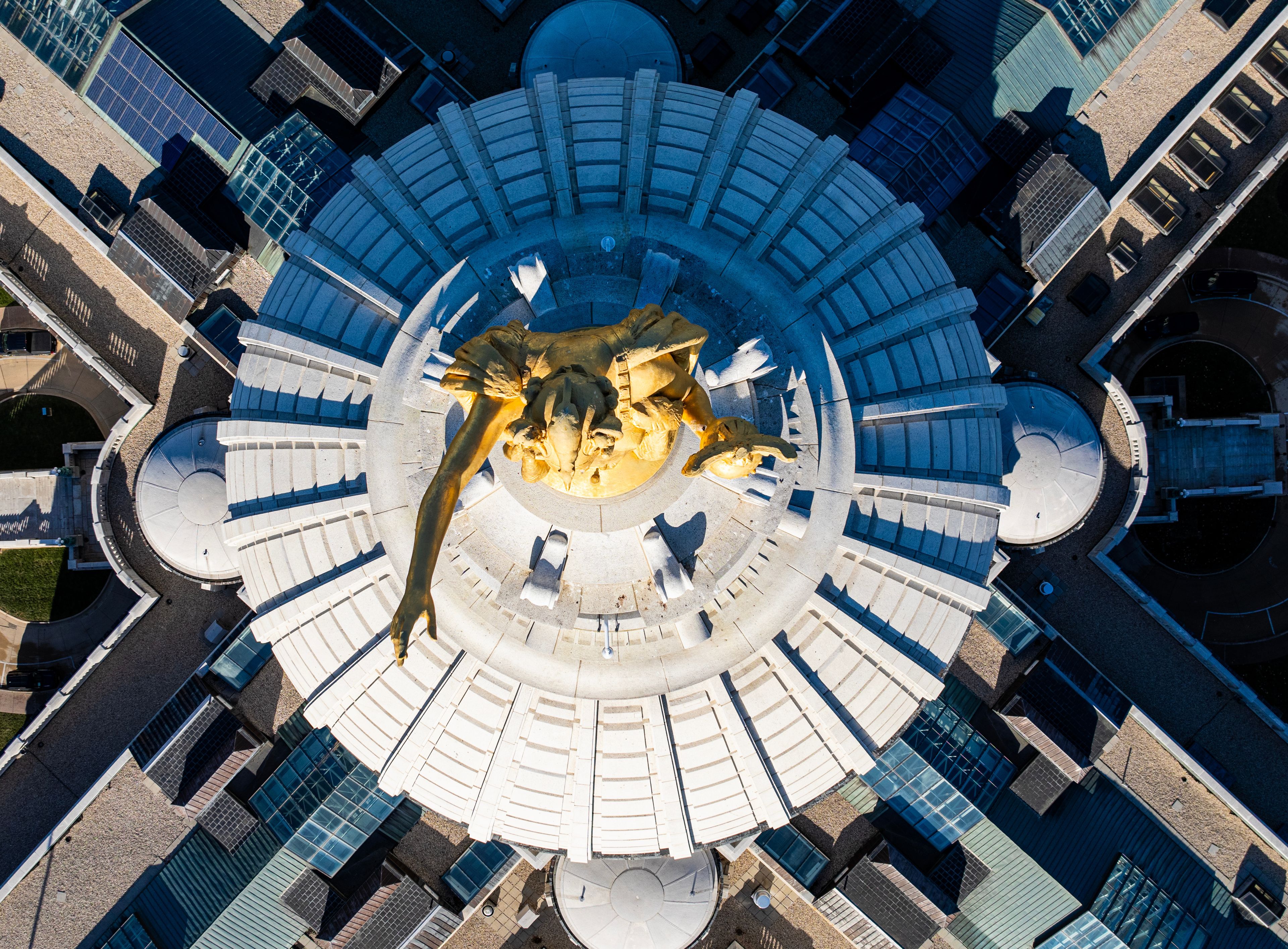 A circular plaza with a central sculpture surrounded by benches.