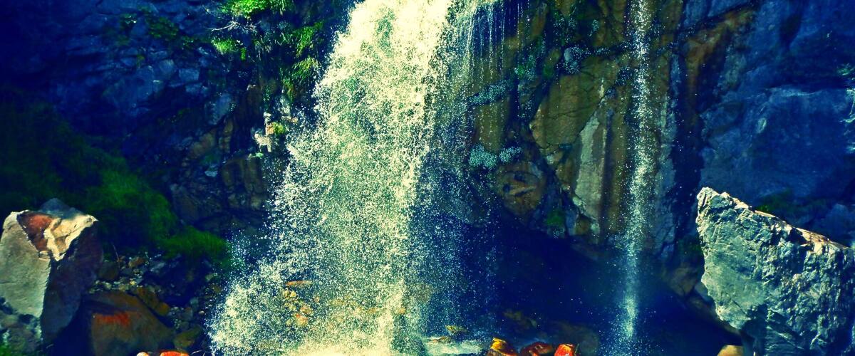 A waterfall cascading over rocks in a lush green landscape.