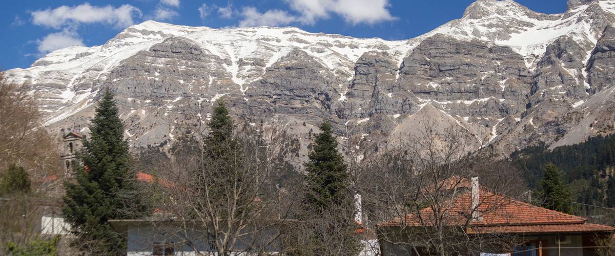 A mountain with snow-capped peaks, a house with a red roof, and a church with a bell tower.