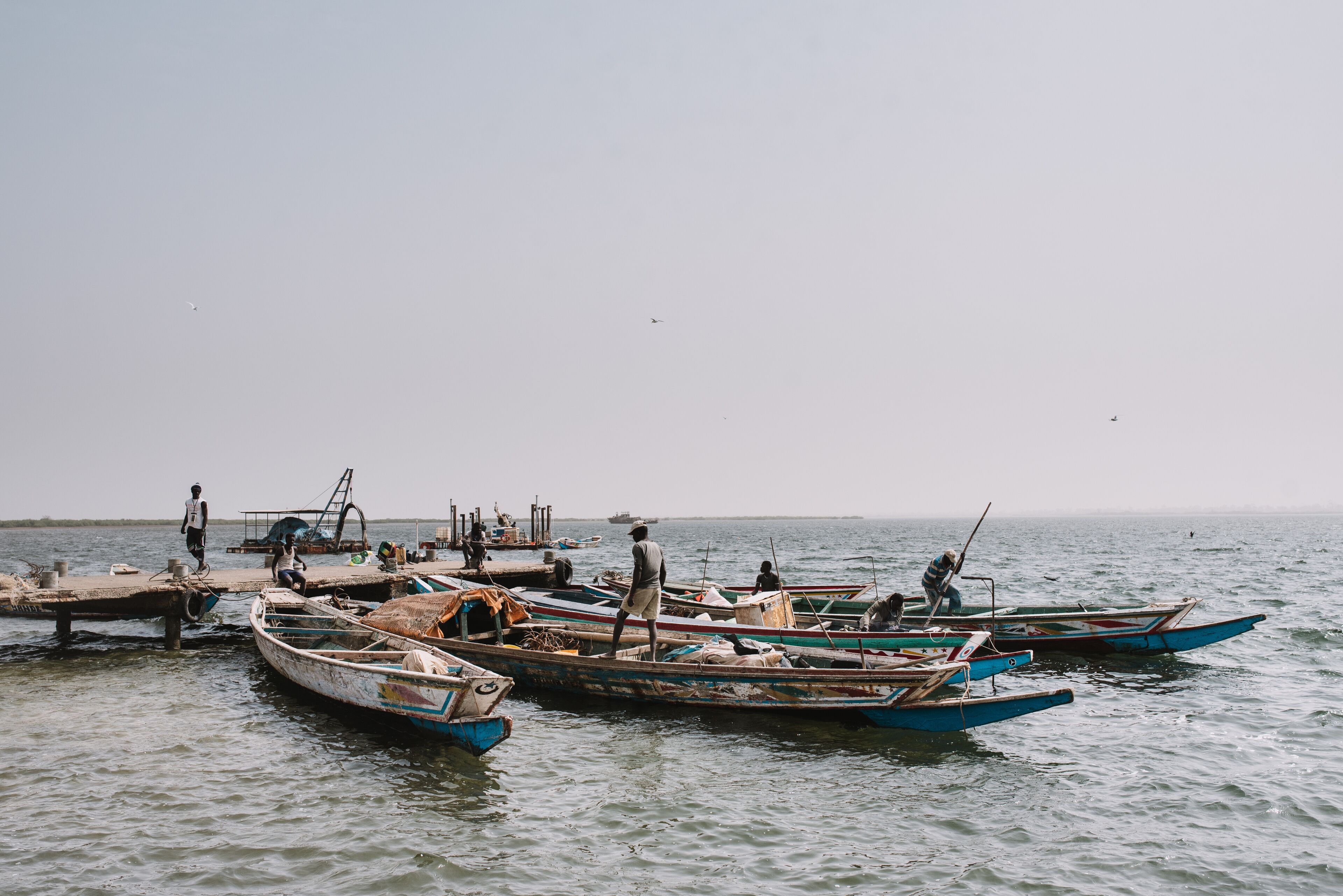 A calm body of water with several small boats docked at a pier.