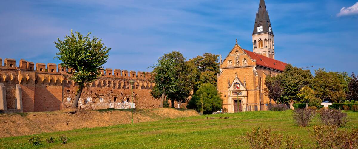 A historic church with a tall tower and a fortified wall.
