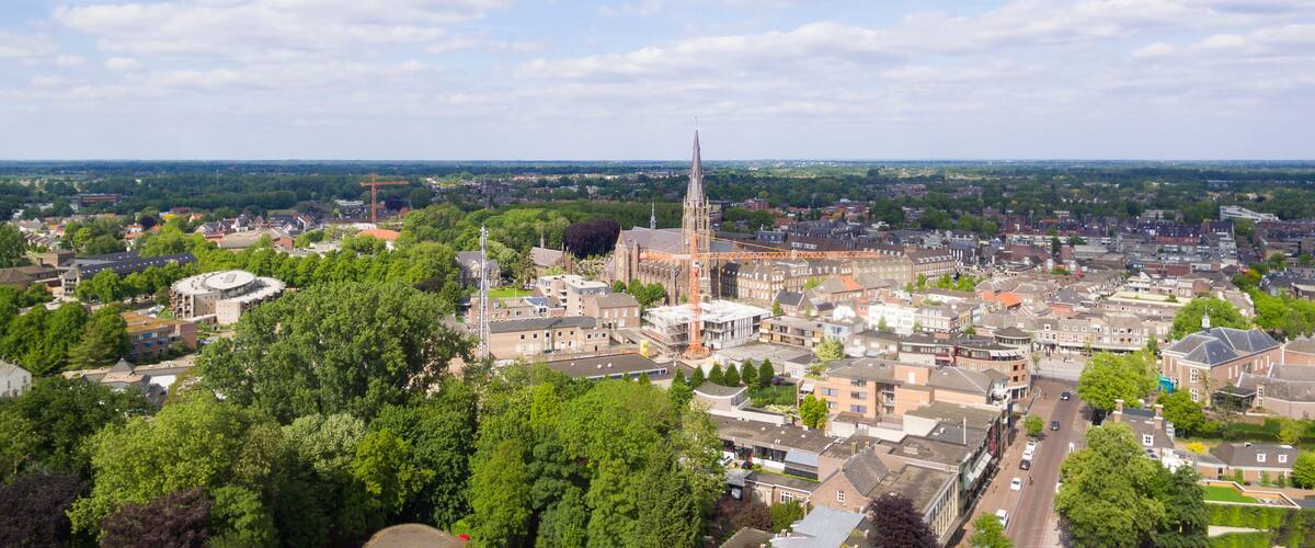 A cityscape with a prominent church tower, dense residential buildings, and surrounding greenery.