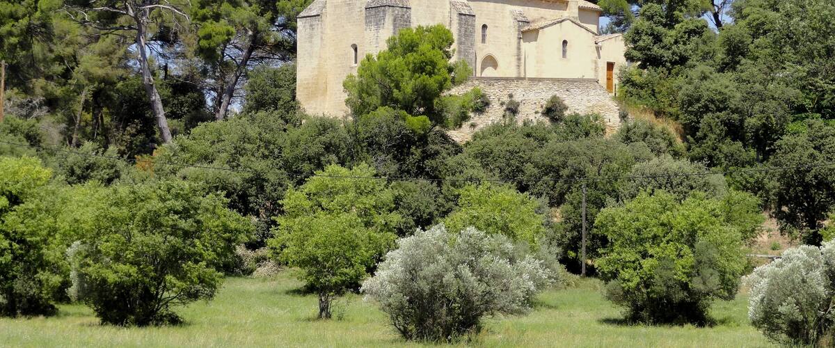 A stone church surrounded by lush greenery and trees.