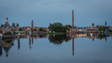 A calm river reflecting historic buildings and a clock tower.