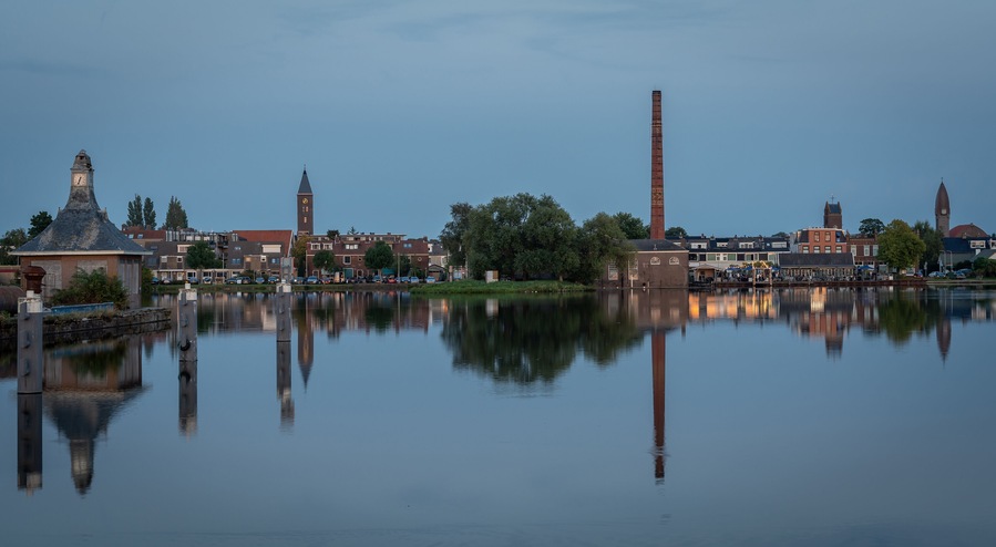 Dutch village Halfweg, which is part of the municipality of Haarlemmermeer, with the Ringvaart canal in the foreground at dusk