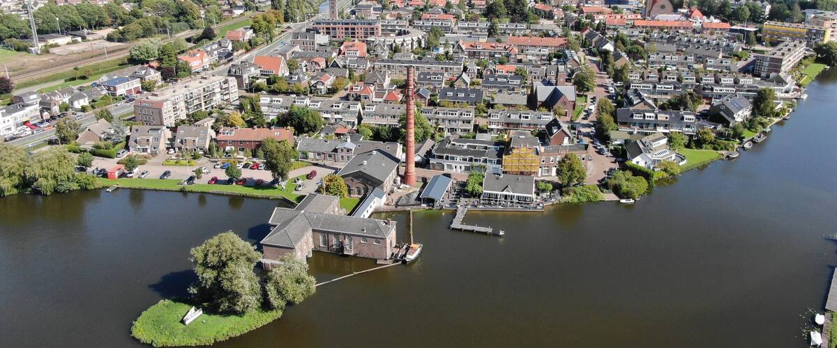 A riverside town with a prominent church tower, a bridge in the background, and a mix of residential and industrial areas.