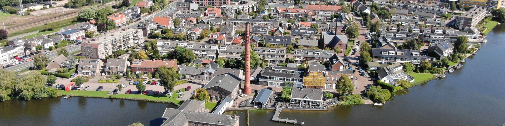 A riverside town with a prominent church tower, a bridge in the background, and a mix of residential and industrial areas.