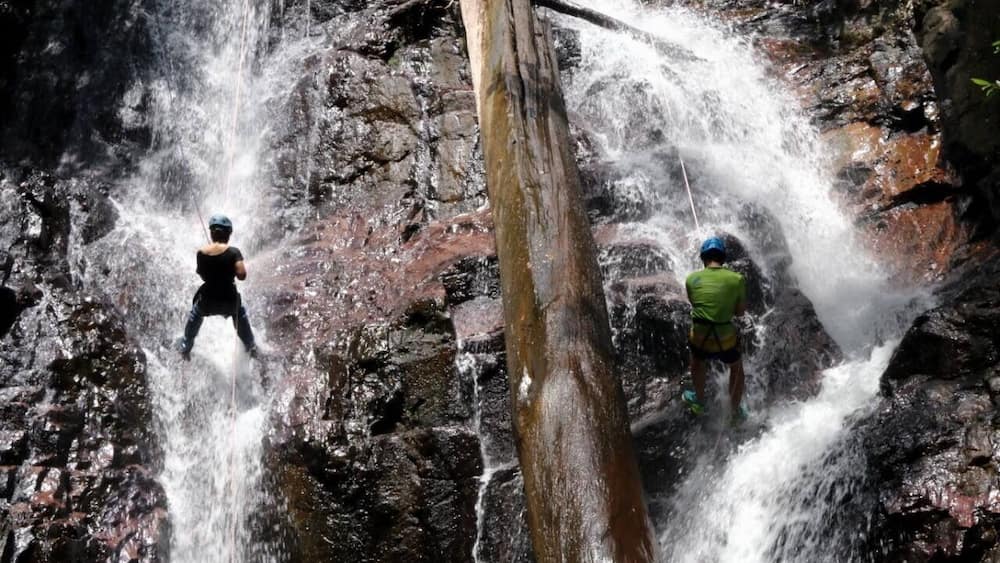 A waterfall with two people standing on rocks.