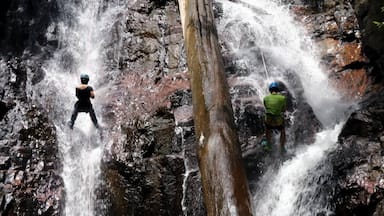 Uma cascata com duas pessoas em pedras.