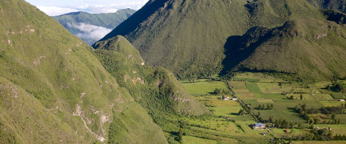 A mountainous landscape with lush green hills and a valley with scattered houses.