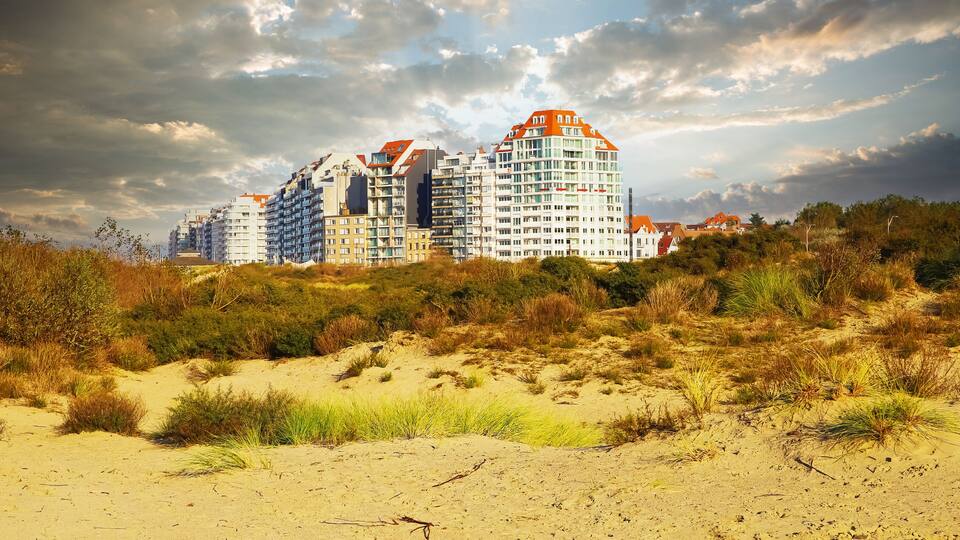 A coastal residential area with modern apartment buildings and dunes.