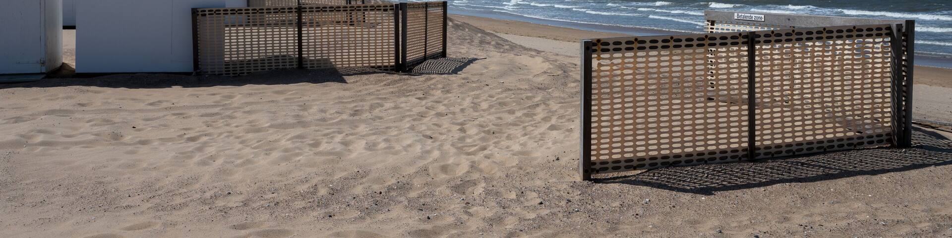 White beach huts on yellow sandy beach in small Belgian town Knokke-Heist, luxury vacation destination, summer holidays