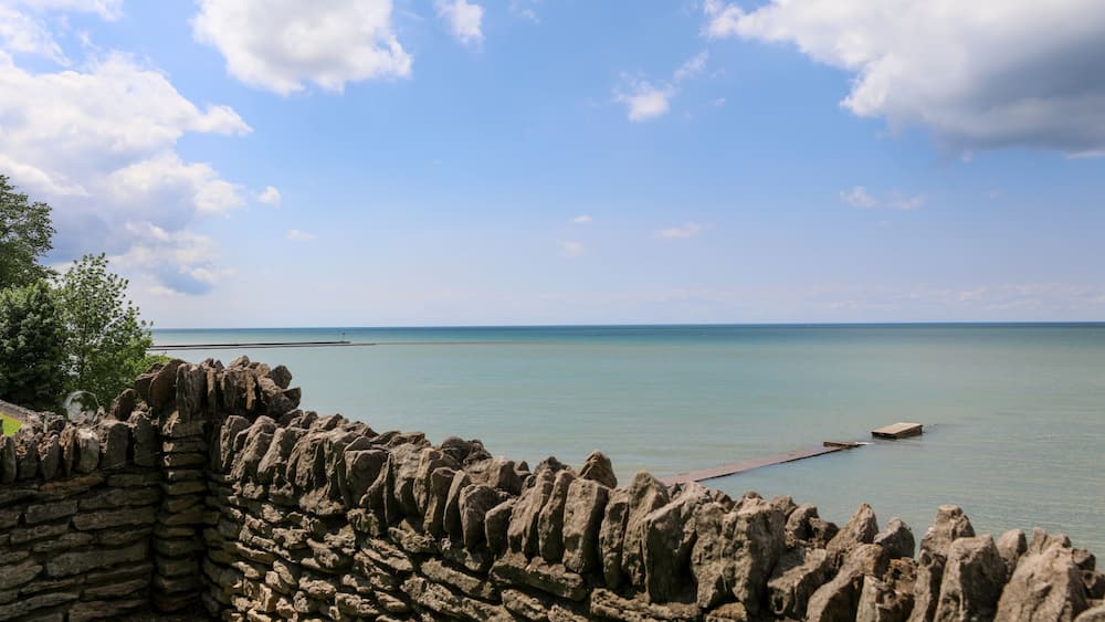 A stone wall, calm sea, and clear sky.
