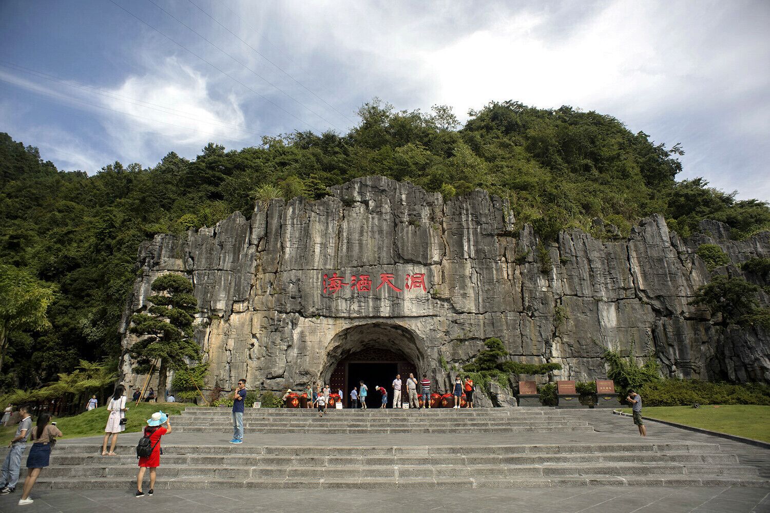 A large rock formation with a cave entrance, surrounded by lush greenery.