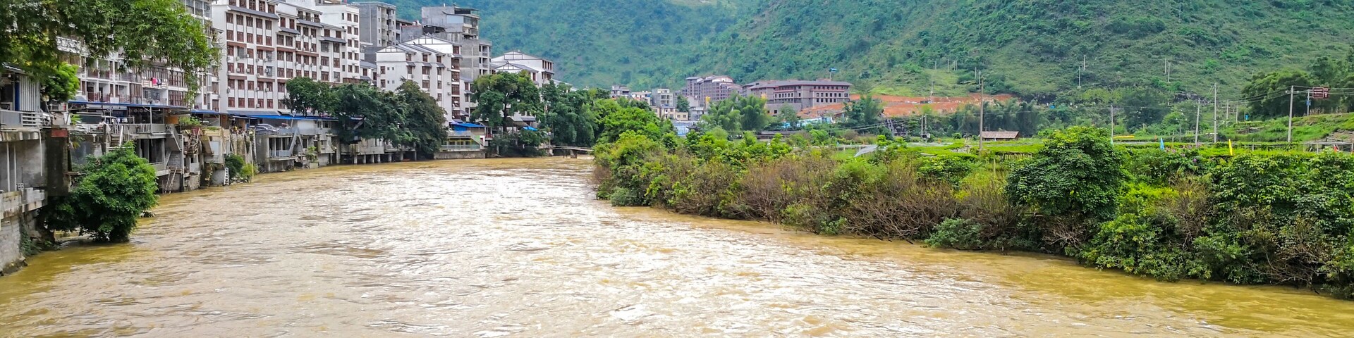 Un río que atraviesa un pueblo con montañas al fondo.