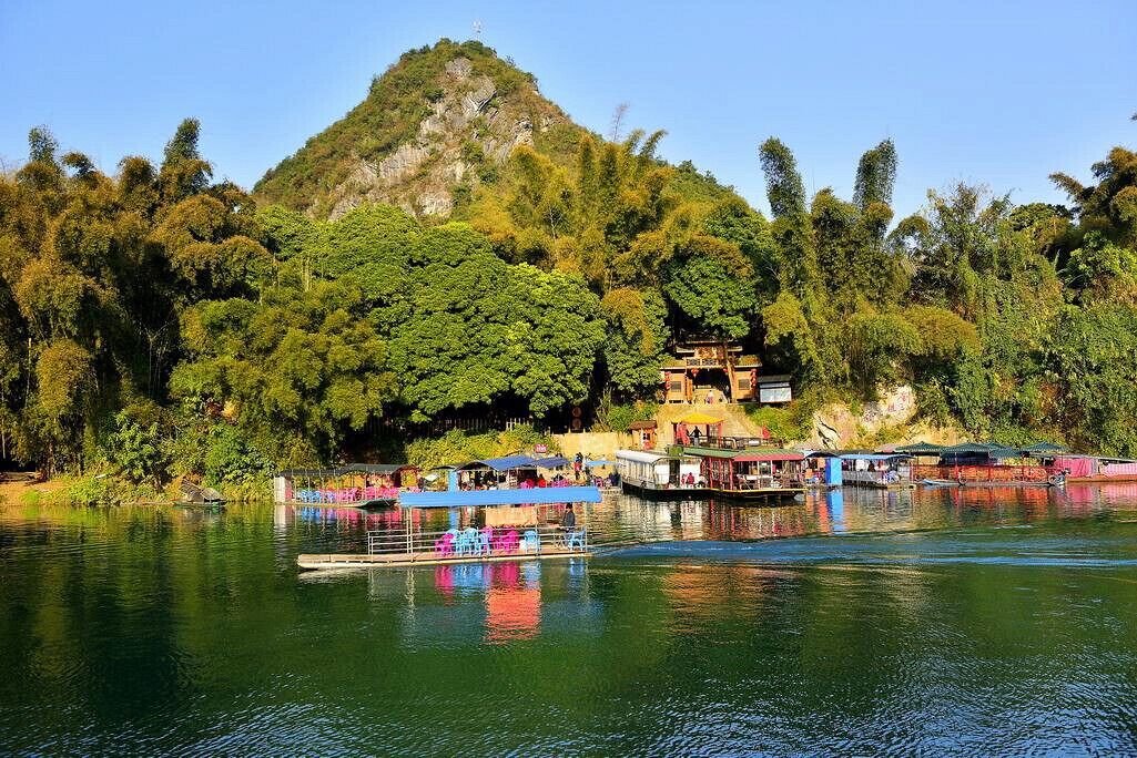 Un río con barcos, una colina con árboles y un edificio sobre la colina.