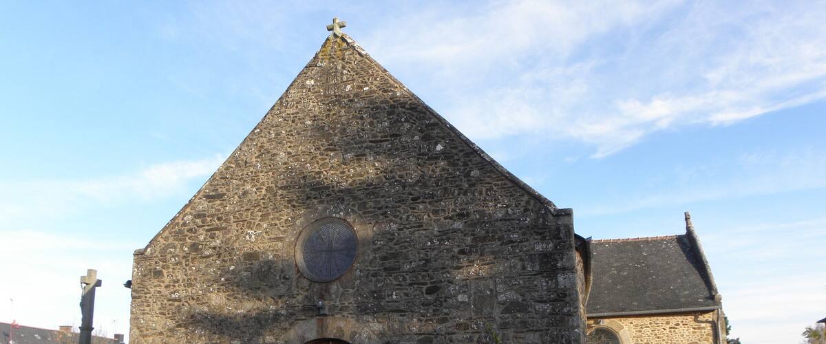 A stone church with a wooden door and a cross on top.
