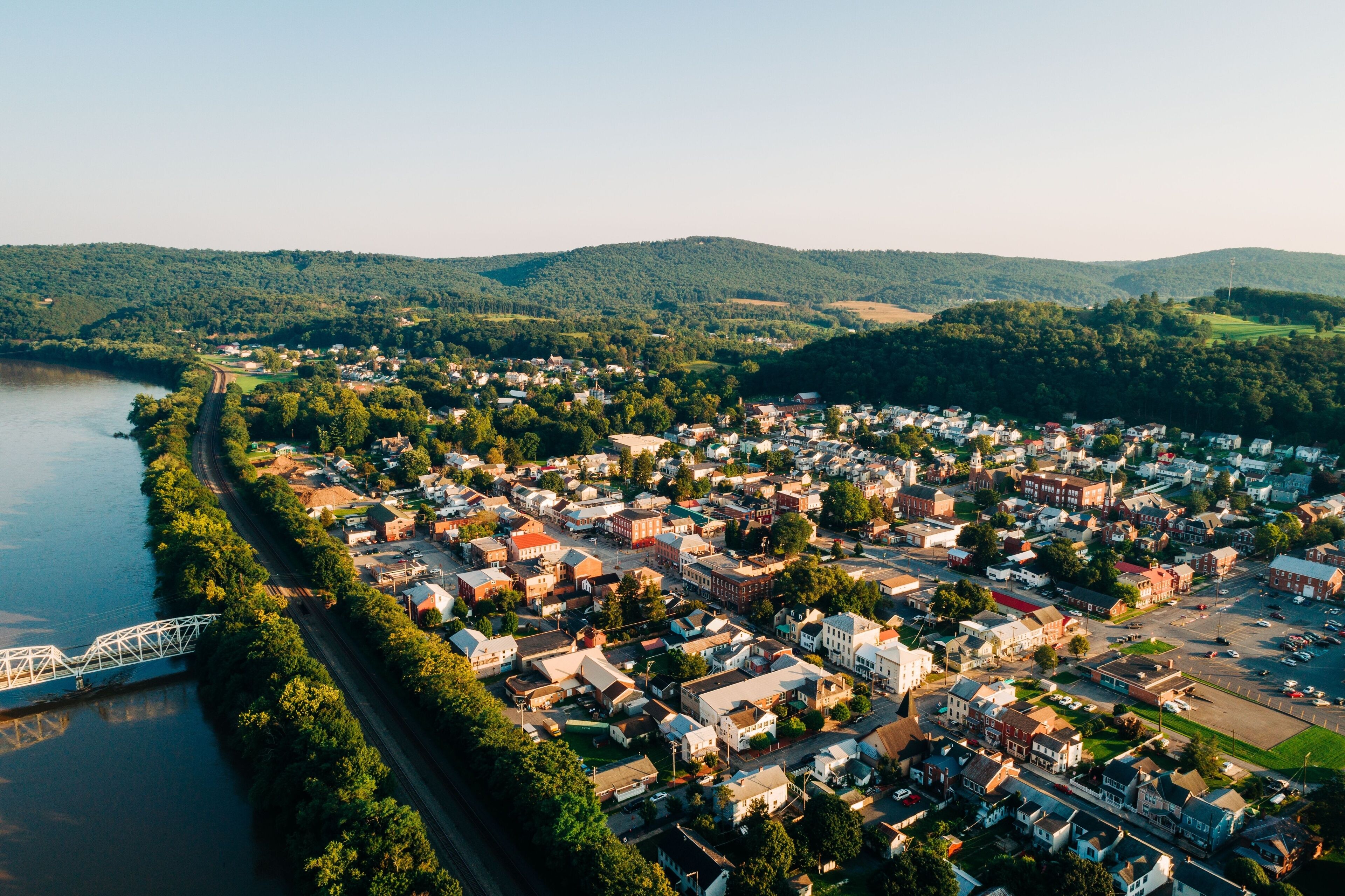 A riverside town with a bridge, surrounded by hills and greenery.