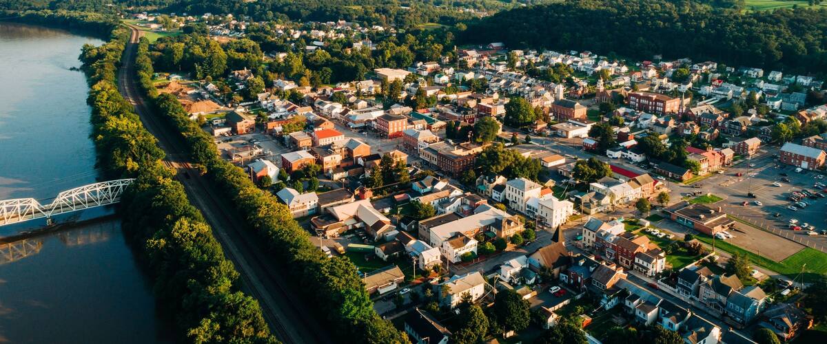A riverside town with a bridge, surrounded by hills and greenery.