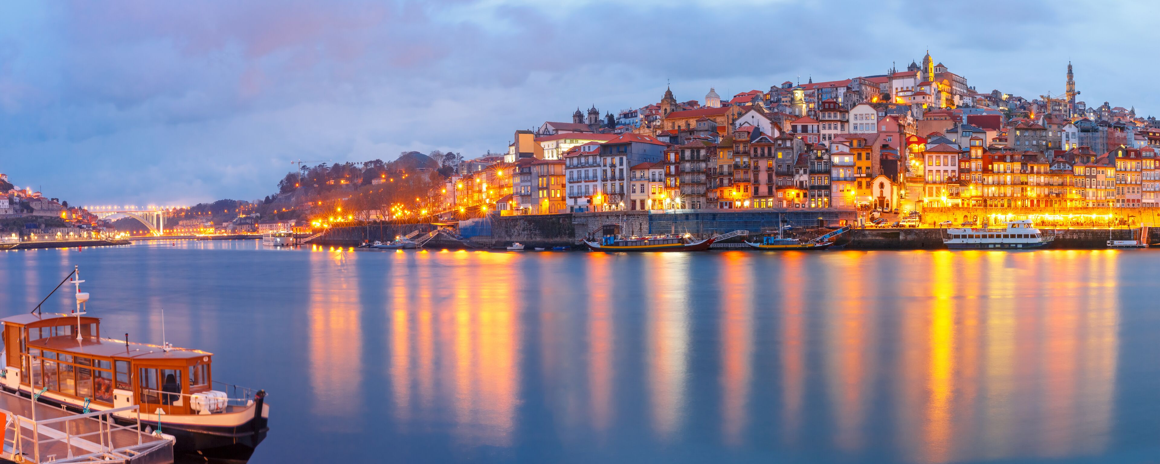 Ribeira and Old town of Porto with mirror reflections in the Douro River during evening blue hour, Portugal, Portugal.
