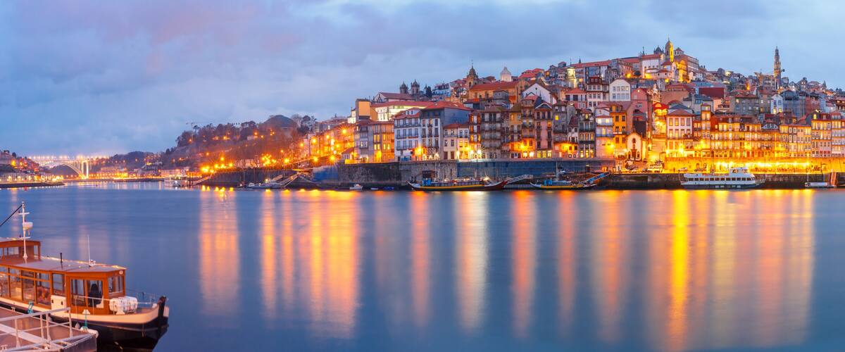 A river with boats, a bridge, and a cityscape with historic buildings.