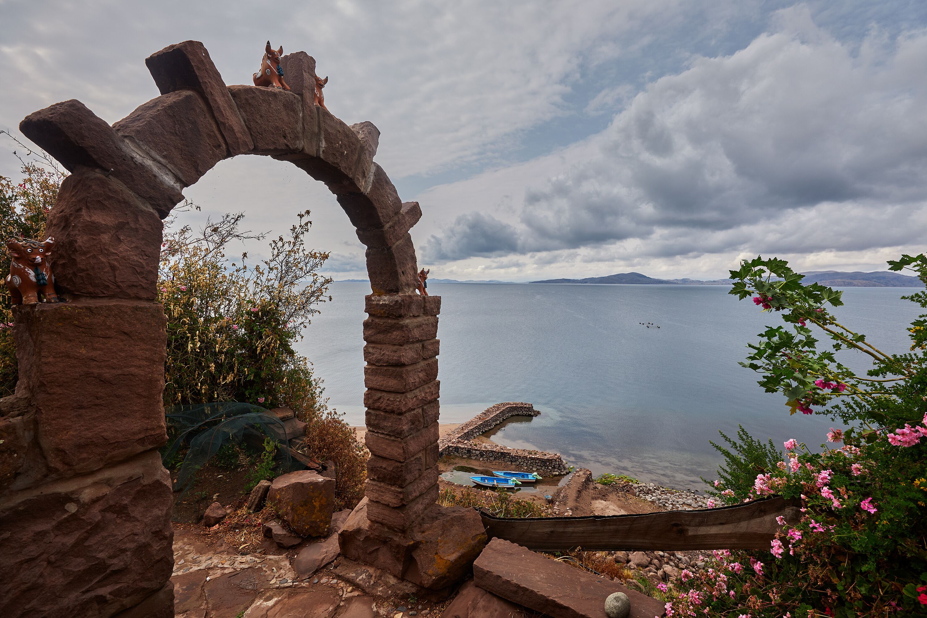 Peaceful corner on the Capachica Peninsula, where flowers embrace a cozy lakeside home and stone benches invite you to pause and admire the vast beauty of Lake Titicaca. Puno Peru