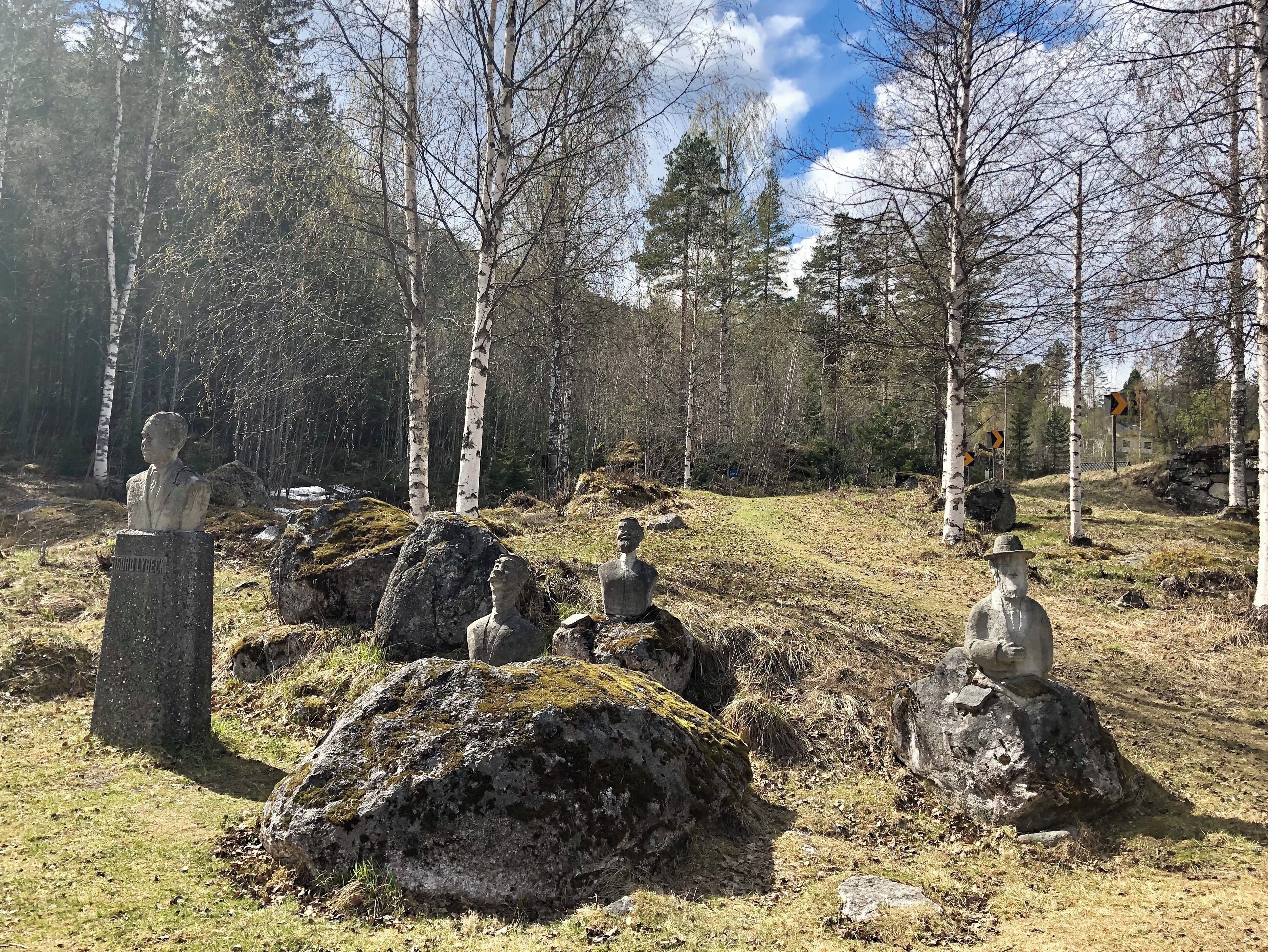 A forest with birch trees and stone sculptures of human figures.
