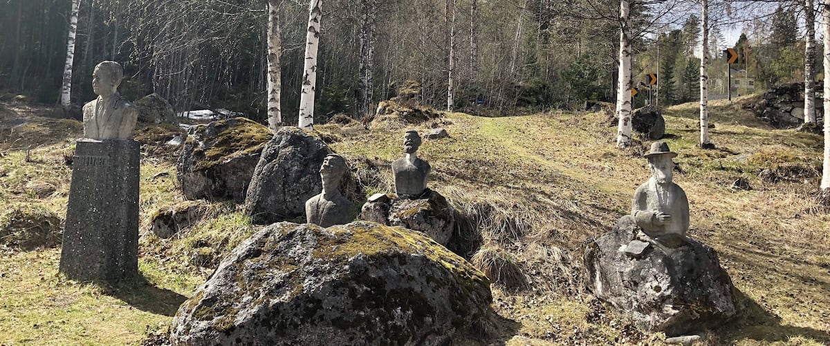A forest with birch trees and stone sculptures of human figures.