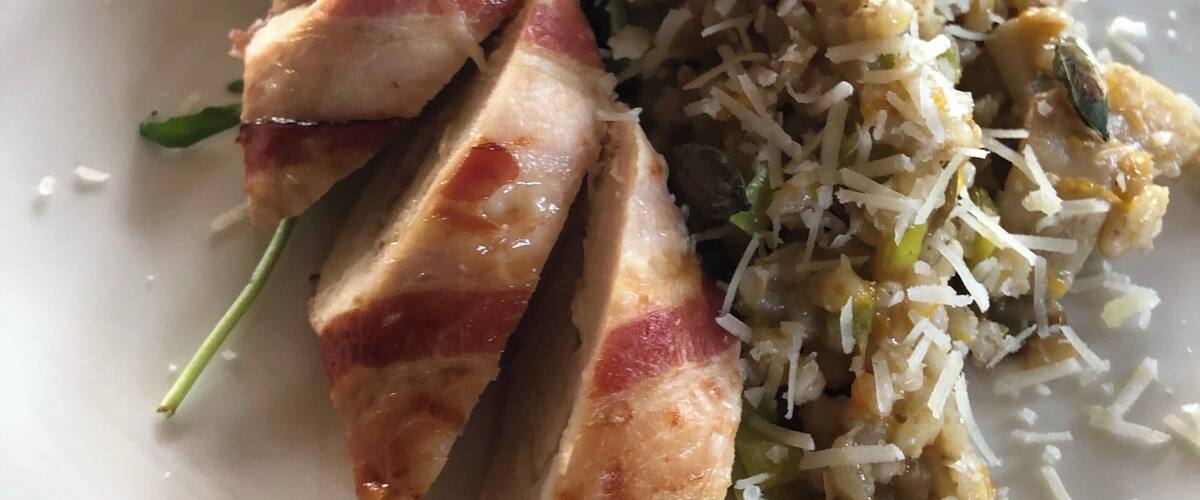 A plate of food with sliced chicken, rice, and greens.