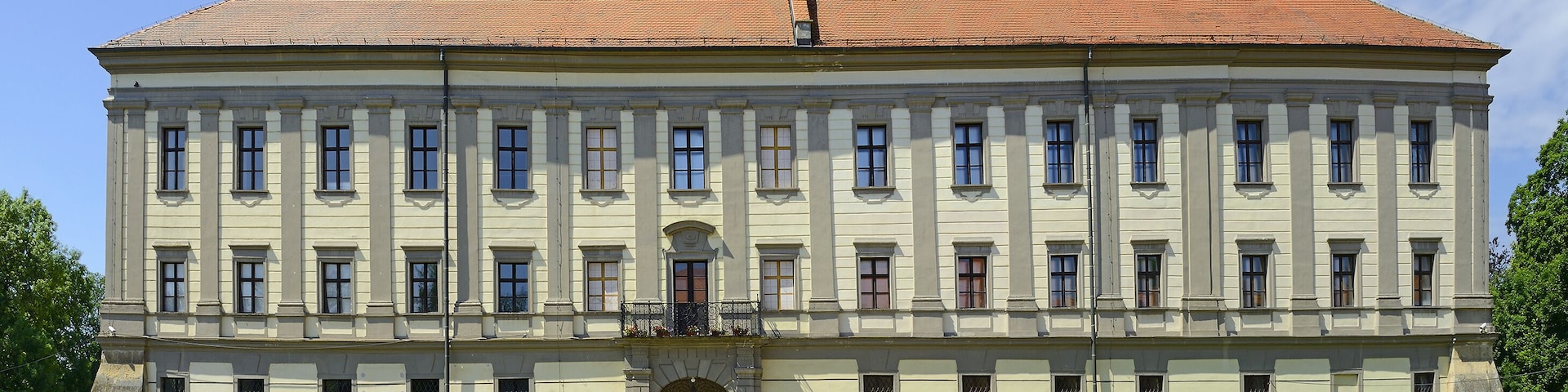 Un edificio grande y de estilo histórico con techo de tejas rojas y numerosas ventanas.