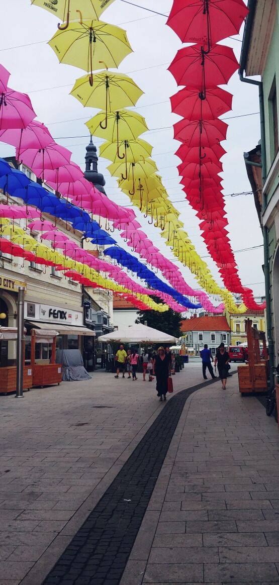 A street lined with colorful umbrellas hanging overhead.