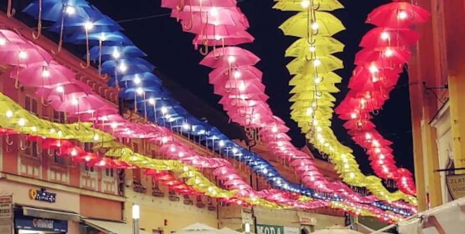 Una calle bordeada de sombrillas coloridas, tiendas y gente.