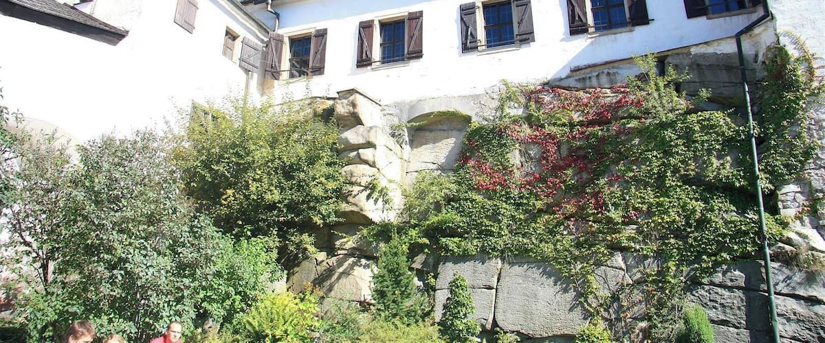 A white building with dark shutters and a stone tower.