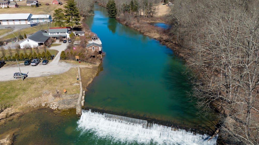 A river flowing through a town with a dam, houses, and a church.
